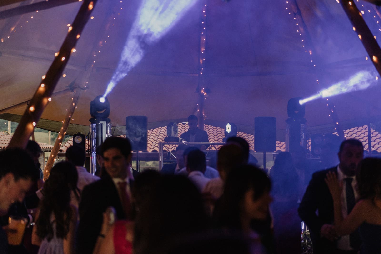 Carpa de boda con guirnaldas y haces de luz sobre la pista llena